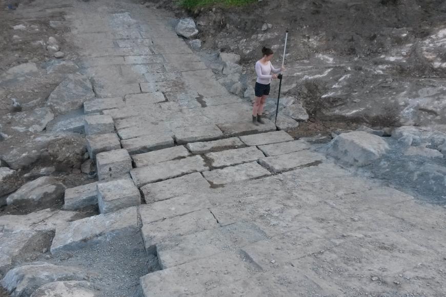 Zu sehen ist ein neu befestigter Weg aus großen Steinquadern, der durch ein trockenes Bachbett führt. 