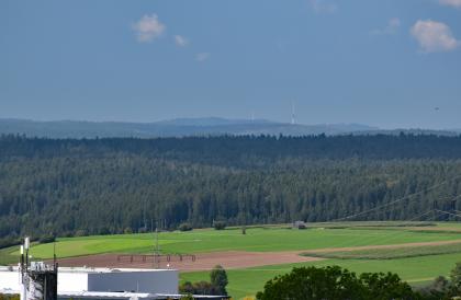 In nordwestliche Richtung blickt man von der Königskanzel über den Nordschwarzwald bis zur Hornisgrinde. Aus großer Höhe blickt man über hochgelegene flache Wiesen und Äcker. Dahinter folgen ausgedehnte, zum Hintergrund hin ansteigende Wälder sowie bewaldete Berge mit Funkmasten.