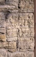 Das Foto zeigt mehrere neben- und aufeinander geschichtete Mauersteine. Die Steine sind waagerecht gefurcht und gelblich braun bis hellgrau gefärbt.