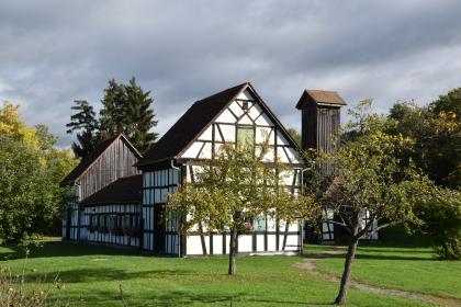 Salinenmuseum „Unteres Bohrhaus“, Rottweil Blick auf eine Ansammlung historischer Gebäude im Fachwerkstil. Die Gebäude, die zum Salinenmuseum „Unteres Bohrhaus“ in Rottweil gehören, stehen auf einer Wiese zwischen Bäumen. Rechts hinten ist ein Förderturm aus Holz erkennbar.