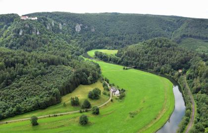 Blick vom Eichfelsen nach Südwesten auf die Flussschlinge der Donau unterhalb von Burg Wildenstein Blick aus großer Höhe auf eine Schlinge der Donau. Der Fluss verläuft von rechts unten zur Bildmitte hin und verschwindet dort zwischen bewaldeten Bergen. Das linke Ufer ist flach, daran schließen sich bewaldete Berge an, die bis zum Hintergrund reichen.