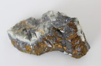 Chalkopyrit (messinggelb) und Galenit (bleigrau) aus der Grube Anton bei Wieden Großaufnahme eines kleinen Gesteinsstückes. Die Bruchseite im Vordergrund zeigt gelbliche bis rötliche sowie dunkelgraue Stellen. Die Oberseite des Gesteins ist weißlich bis grau und kristallin.