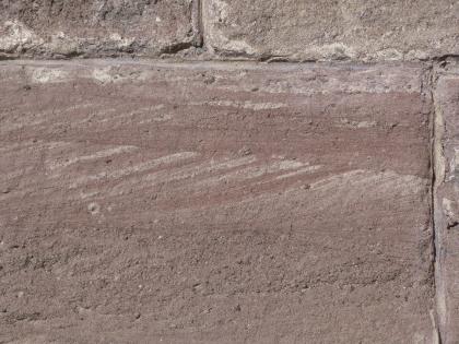 Mauerquader aus Degerfelder Sandstein am Breisacher Münster Nahaufnahme eines rötlich grauen Mauersteins mit teils waagrechter, teils schräger Schichtung sowie gröberen Poren unten. Oben und rechts sind weitere Mauersteine angefügt.
