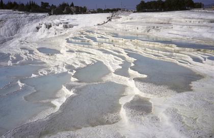 Pamukkale in der Türkei, terrassenförmiges Travertinvorkommen Das Bild zeigt ausgedehnte, weißliche Gesteinsterrassen. Zwischen den einzelnen Terrassen fließt oder steht Wasser.