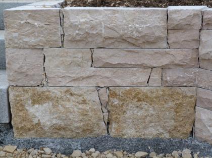 Gartenmauer aus Tuttlinger Marmor Teilansicht einer Steinmauer. Der untere Teil zeigt grünlich braune Quader, darüber sind die Steine rötlich grau. Breite Fugen zwischen den Steinen sind mit kleinen Bruchstücken gefüllt.