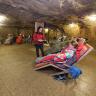 Blick in die Halle eines ehemaligen Bergwerkes. In dem gut ausgeleuchteten, mit Bodenfliesen bedeckten Raum sind mehrere Liegstühle aufgestellt. Die Stühle sind mit Menschen in Warmhaltedecken besetzt.