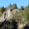 Blick auf eine gerundete, felsige Bergkuppe mit teilweiser Bewaldung. Die Felsen links am dortigen Berghang sind besonders markant. Rechts unten scheinen weitere Felsen zwischen den Bäumen hindurch. 