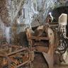 Gezeigt werden hier ehemalige Arbeitsgeräte in einem Besucherbergwerk: Wurfschaufellader und Bohrwagen, abgestellt vor einer linksseitig verlaufenden grauen Stollenwand.