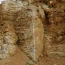 Das Bild zeigt eine ockerfarbene, gelb-braune Steinwand. Die Oberfläche der Wand ist sehr unregelmäßig und im Gestein sind verschiedene Strukturen zu erkennen, wie zum Beispiel aufgeweitete Klüfte, Schlote oder Lösungsspuren.
