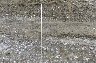 Teilansicht einer Gesteinswand mit (von oben): feinem Kies, eingebettet in Sand, einer glattgestrichenen Schicht sowie gröberem Kies, der ebenfalls von Sand umlagert ist. Links ist ein Zollstock angelehnt.